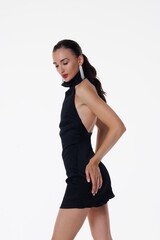 Beautiful young woman in a black elegant dress posing in studio on white background. Fashion model...
