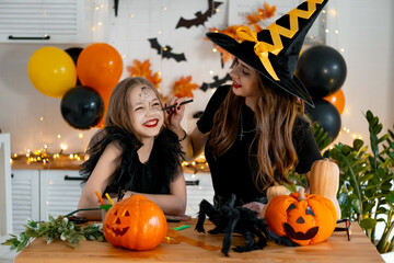 A happy family is getting ready for Halloween. Mother and child daughter in carnival costumes at...
