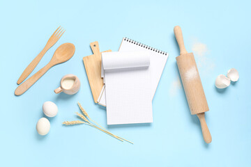 Composition with blank recipe book, wooden kitchen utensils, milk and eggs on color background