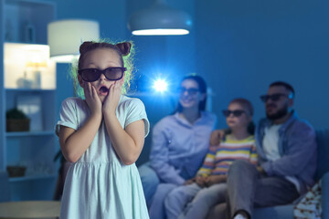 Shocked little girl with 3D glasses and her family watching cartoons at home in evening