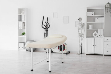 Interior of physiotherapist's office with couch, exercising bike and human skeleton