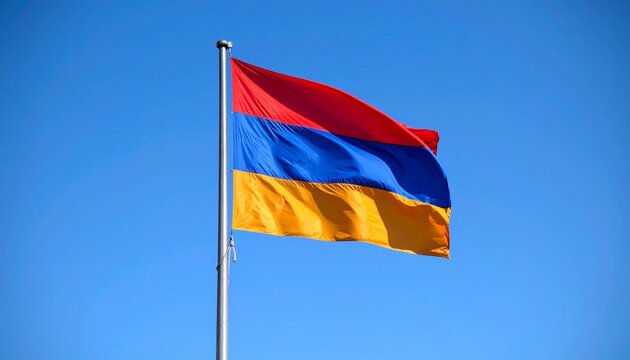 Armenian national flag waving against a clear blue sky,