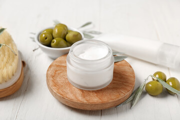 Natural cosmetic products, green olives and massage brush on light wooden background