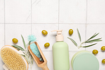 Composition with natural cosmetic products, massage brush and green olives on light tile background