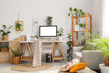 Interior of office with workplace, sofa and green plants