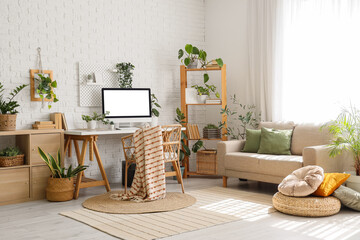 Interior of office with workplace, sofa and green plants