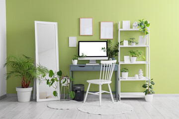 Interior of office with workplace, mirror and green plants