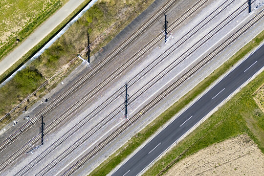 Aerial view of parallel lines of transportation infrastructure contrasting with the natural landscape, including railways and roads, Deutschlandsberg, Steiermark, Austria.