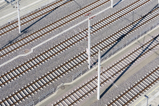 Aerial view of parallel train tracks gleaming under the sun, creating a rhythmic pattern of steel and gravel, Deutschlandsberg, Steiermark, Austria.