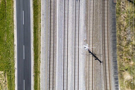 Aerial view of parallel lines of asphalt, railway track and grassy border create a geometric landscape from high above, Deutschlandsberg, Steiermark, Austria.