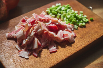 Preparation of ingredients for home cooking. Smoked bacon slices and chopped spring onion on a...
