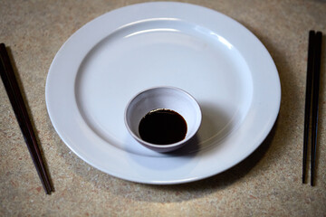 Soy sauce served in a white bowl with wooden chopsticks for dining