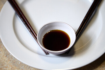 Close view of soy sauce in a bowl with chopsticks on dining table