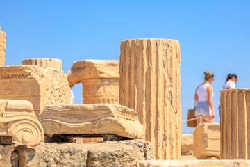 A group of people are walking past a row of ancient columns, Acropolis in Athens