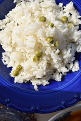 Boiled white rice with green peas in a blue plate