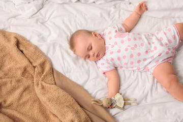 Cute sleeping little baby with bunny toy on bed at home