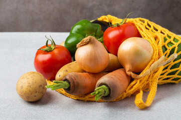 Fresh vegetables in a reusable eco bag on a gray background. The concept of healthy eating, farm...