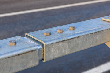 Close-up of steel road divider with bolts on asphalt highway