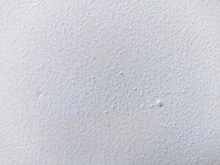 White painted wall surface with small bubbles and textured imperfections caused by paint application