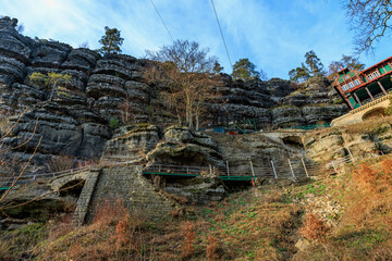 Stunning rocky cliff landscape with stairway and autumn foliage in daylight