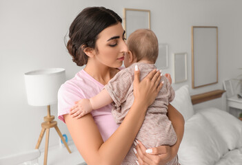 Young mother cradling her baby for sleep in bedroom at home