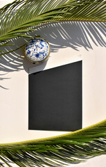 Mockup template with black blank round decorative casket and palm leaves on white background 