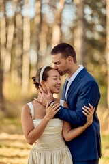 Fototapeta premium Romantic Couple Embracing Outdoors in a Sunlit Forest Wedding Portrait