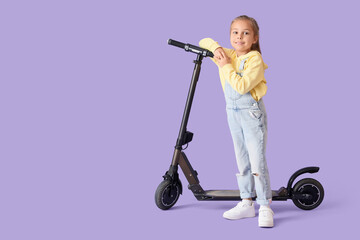 Cute little girl with electric scooter on lilac background