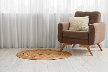 Armchair and rug near light curtain in living room