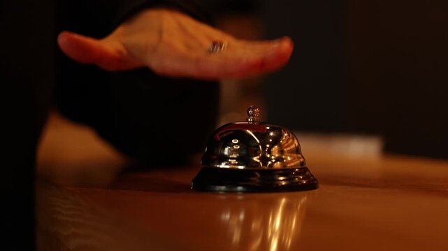 Close up hand of unrecognisable woman impatiently pressing the bell at hotel reception desk. Ring bell for customer service, hospitality and help. Check in, welcome and help with service alert.