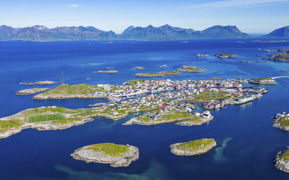 Aerial view of a vibrant fishing village nestled amongst the rocky islands, with cobalt waters contrasting against the bright houses, Henningsv&Atilde;&brvbar;r, Nordland, Norway.