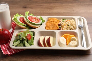 Plastic tray with tasty food, milk and fork on wooden table, closeup. School lunch