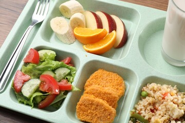 Plastic tray with tasty food and fork on table, closeup. School lunch