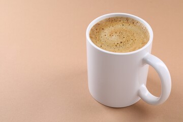 Aromatic coffee in cup on beige background, closeup. Space for text