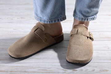 Woman in stylish beige slippers on light wooden floor, closeup
