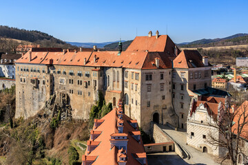 Historic czech castle with red roofs under blue sky in scenic countryside