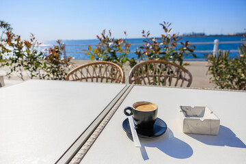 Espresso on seaside cafe table with sunny ocean view and natural decor