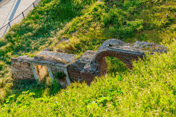 Ancient ruins amidst greenery with stone and brick arch structure