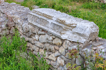 Ancient stone wall with intricate carved details in lush green surroundings