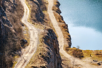 Scenic aerial view of quarry lake with winding dirt roads and rocky cliff