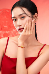 Portrait of a young woman in red attire with a decorative bracelet against a vibrant background.