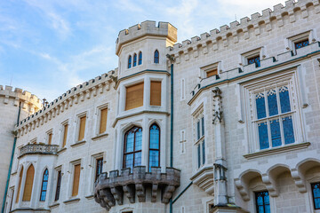 Fototapeta premium Gothic-style medieval castle facade with tower and arched windows against blue sky