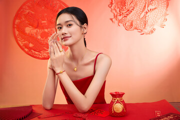 Naklejka premium Young woman in red dress showcasing traditional decorations and jewelry Chinese word means good luck.