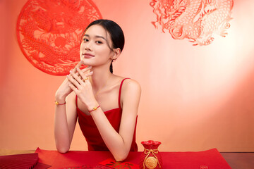 Confident young woman in red attire with elegant pose against decorative backdrop.
