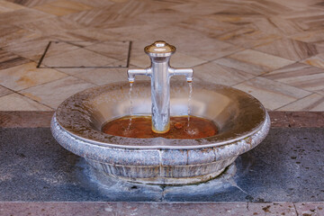Ornate metal fountain with dual streams in public stone setting