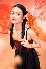 Young woman with braids holding a decorative fish, smiling brightly against a colorful background.