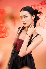Female model with braided hair posing elegantly in a vibrant, warm-toned background.
