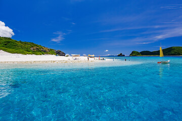 Fototapeta premium 無人島の嘉比島が見える。 白砂のビーチには観光客が上陸している。 パラソルやボート、サバニ（沖縄特有の双胴船）も見える。 船上からも水底の様子が見える。 素晴らしい透明度。 沖縄県島尻郡慶良間諸島座間味島嘉比島-2025/6/27 