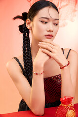 Young woman with braided hair poses gracefully with jewelry against a warm backdrop Chinese word...