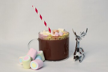 Hot cocoa cup with marshmallows and festive striped straw on white background — perfect cozy...